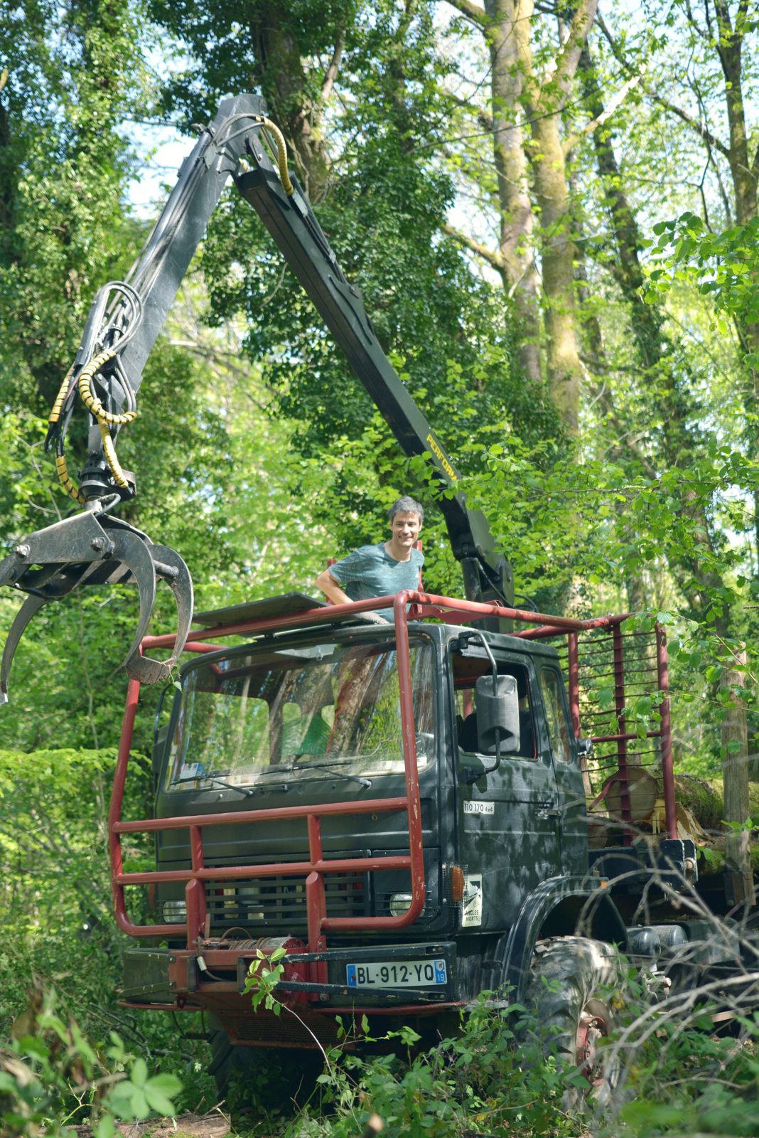 Le même camion, grue déployée dans le sous-bois