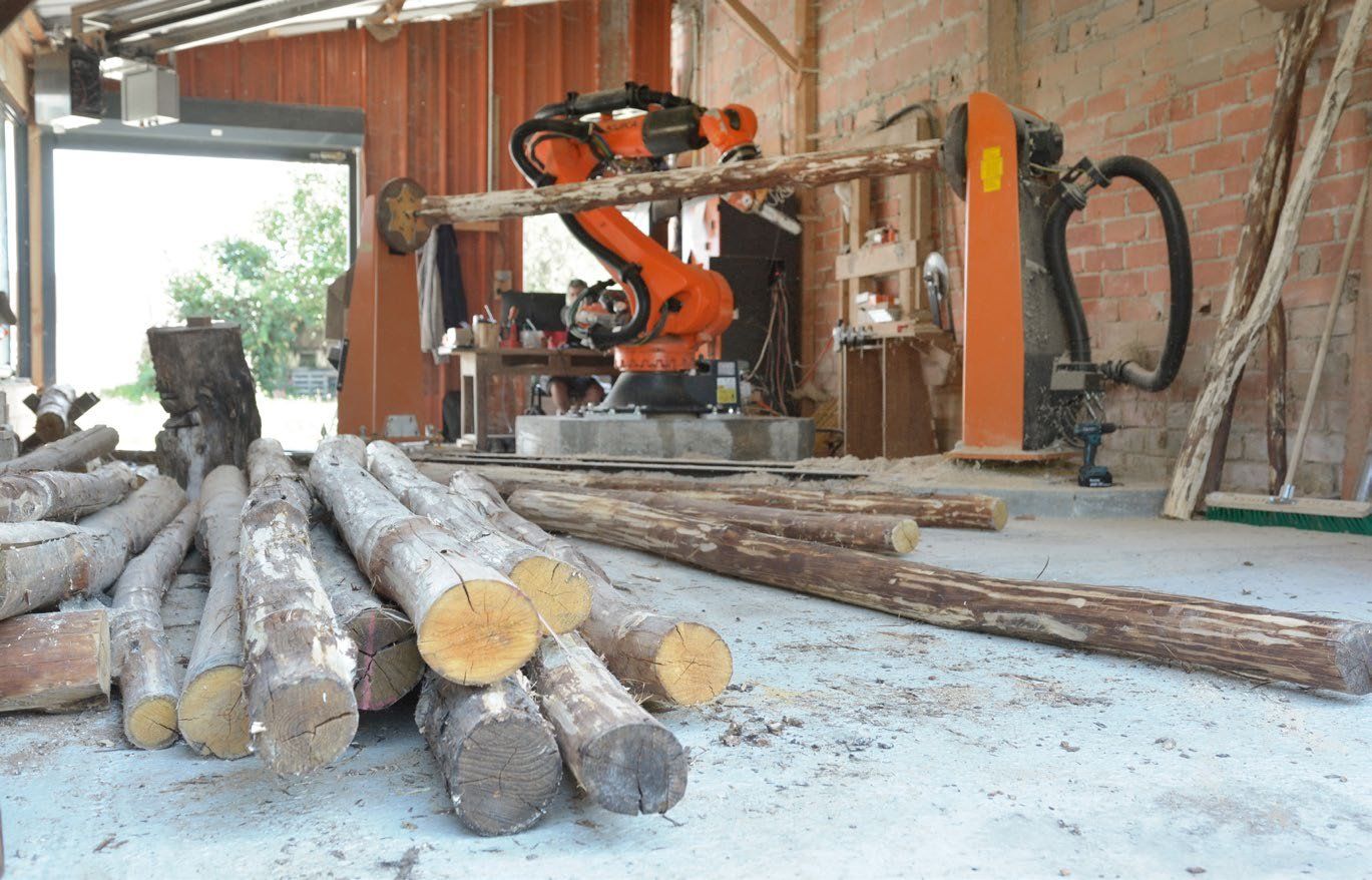 Raw felled logs stacked in the workshop before robotic shaping