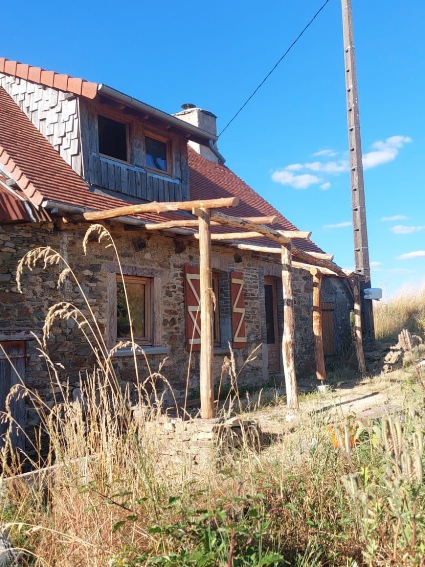 Wood-framed pergola built onto a traditional stone house